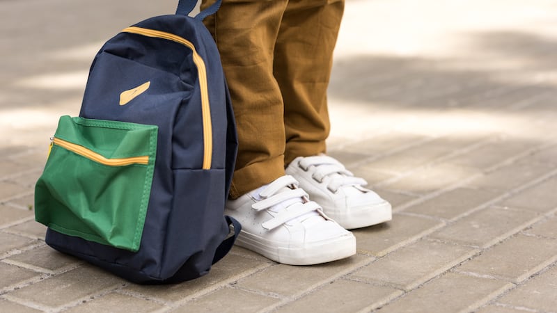 cropped shot of stylish schoolboy standing with backpack on street
